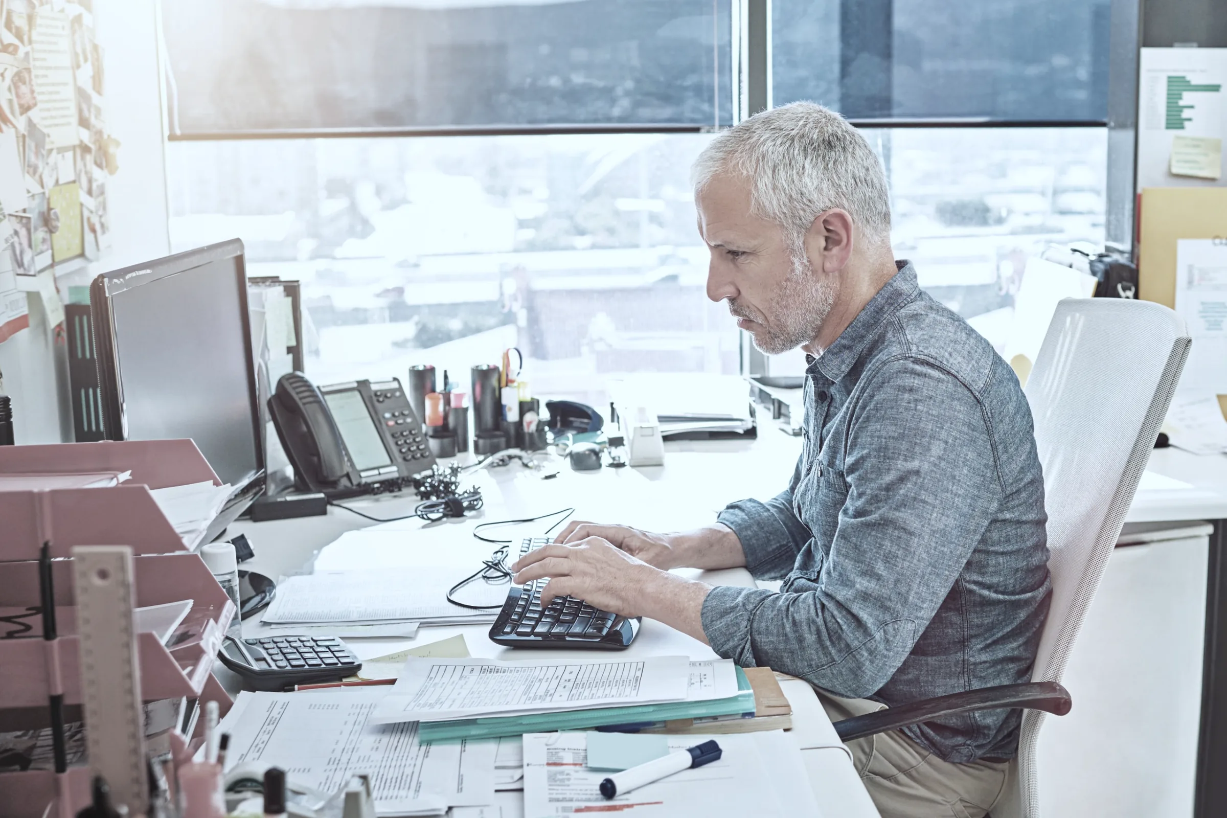 A supply planner working through printed plans at his desk